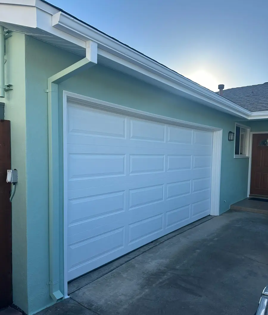After: garage and front of home finished in a smooth seafoam exterior coating with white trim and gutters
