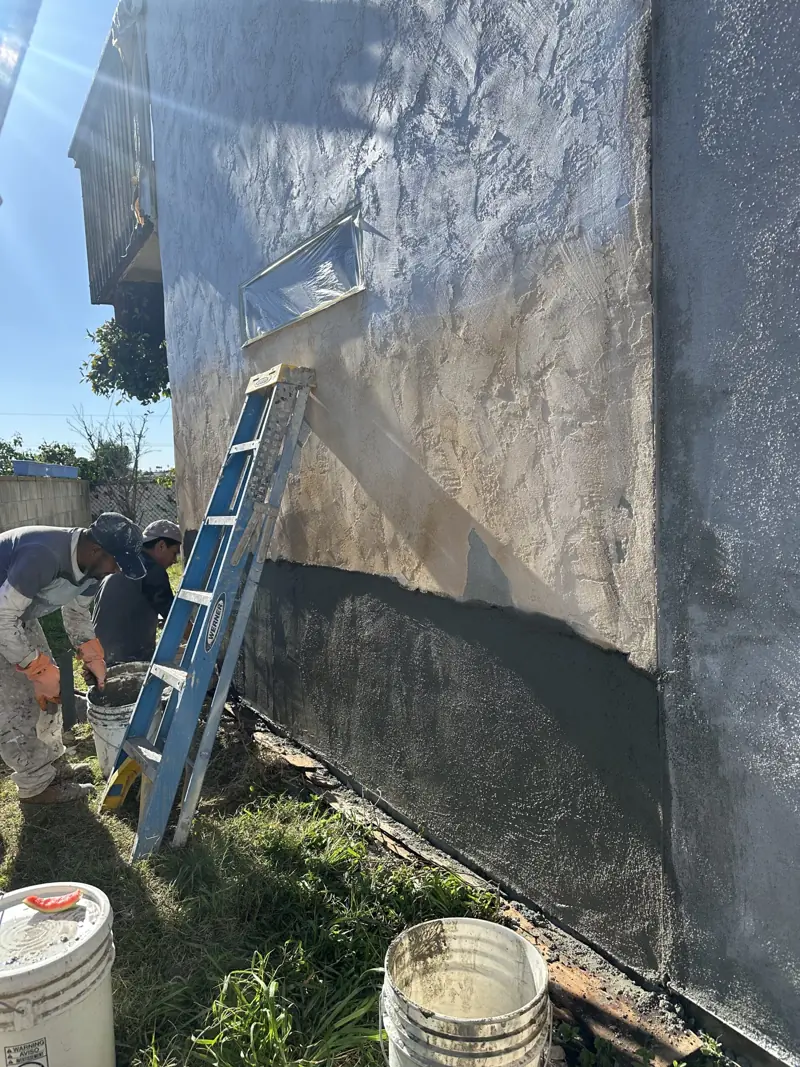 Lotus Remodeling crew member repairing and preparing a stucco wall before applying exterior coating