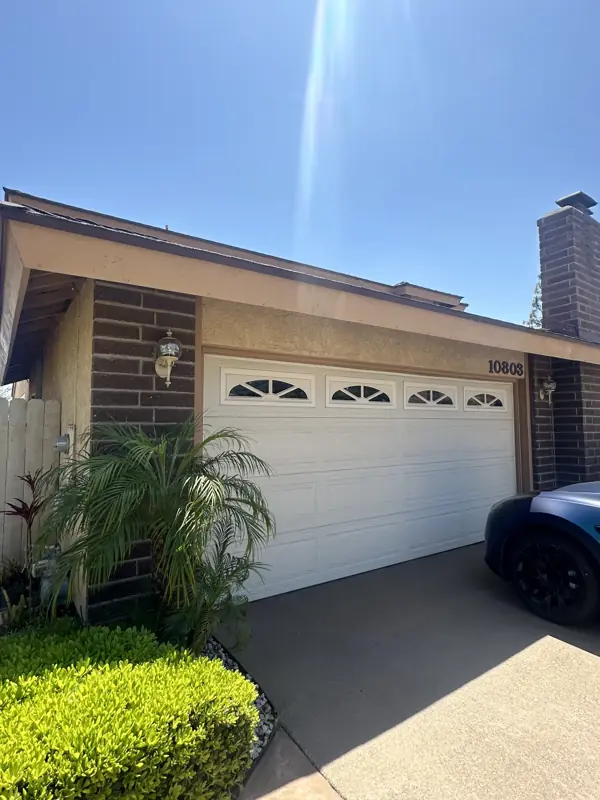 Two-tone exterior coating on a home with a white garage door and brick accent wall