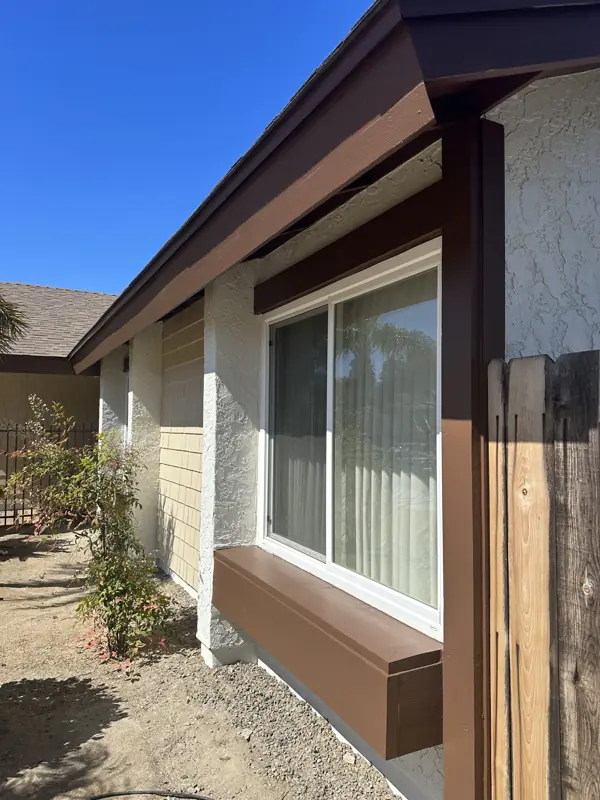 Light stucco exterior with dark brown fascia and window trim, freshly coated
